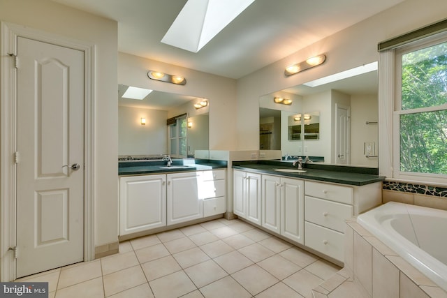 bathroom featuring tile floors, tiled bath, vanity, and a skylight