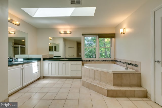 bathroom with tile flooring, tiled bath, a skylight, and vanity