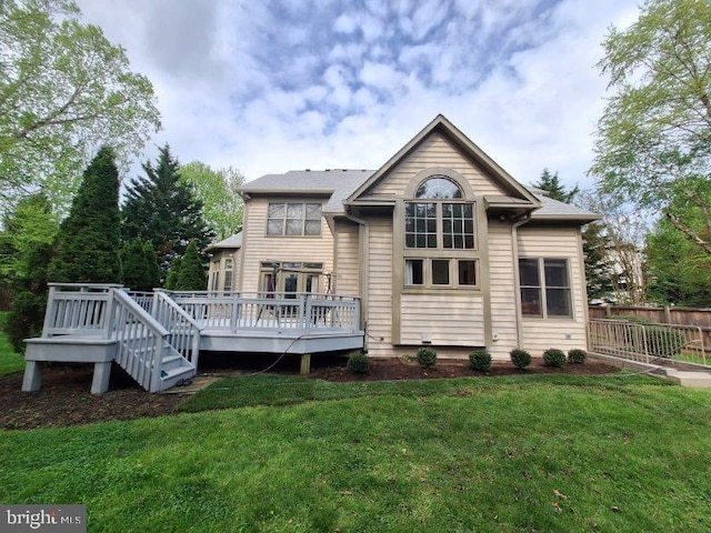 back of property featuring a deck and a lawn