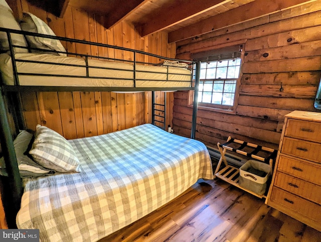 bedroom with wood walls, beam ceiling, and dark hardwood / wood-style flooring