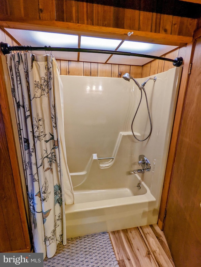 bathroom with wood-type flooring and shower / bathtub combination with curtain