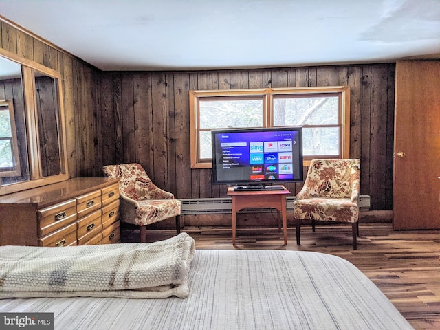 living area featuring a wealth of natural light, baseboard heating, wooden walls, and hardwood / wood-style flooring