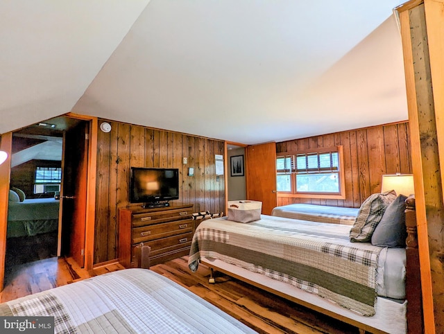 bedroom with wooden walls, vaulted ceiling, and hardwood / wood-style floors