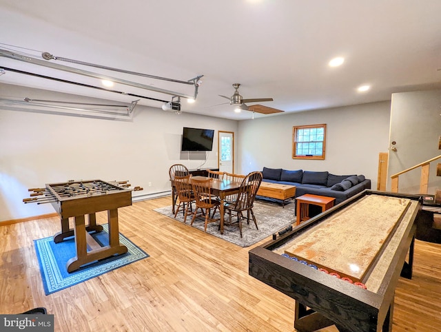 rec room with light hardwood / wood-style floors, a baseboard radiator, and ceiling fan