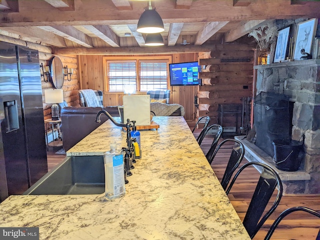 interior space featuring beam ceiling, stainless steel fridge, hardwood / wood-style floors, and decorative light fixtures