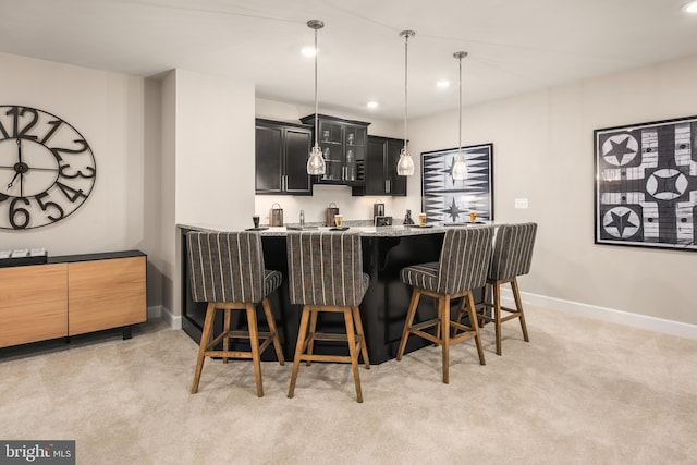 kitchen featuring a kitchen breakfast bar, kitchen peninsula, light carpet, and light stone countertops