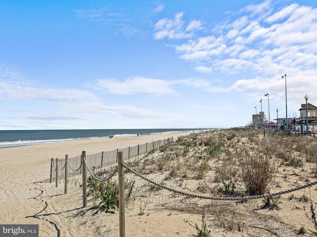 view of water feature featuring fence and a view of the beach