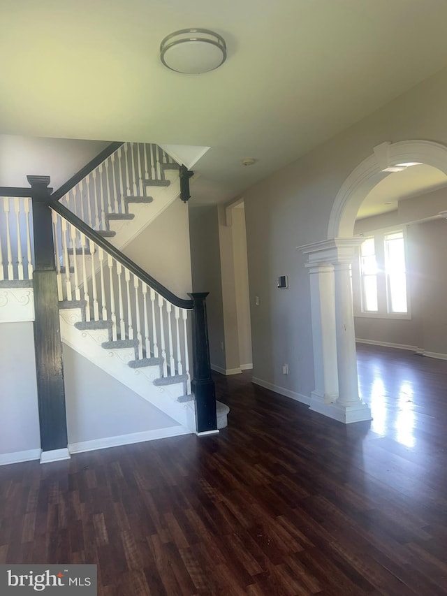 staircase featuring dark hardwood / wood-style flooring and ornate columns