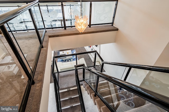 stairs featuring a notable chandelier and carpet