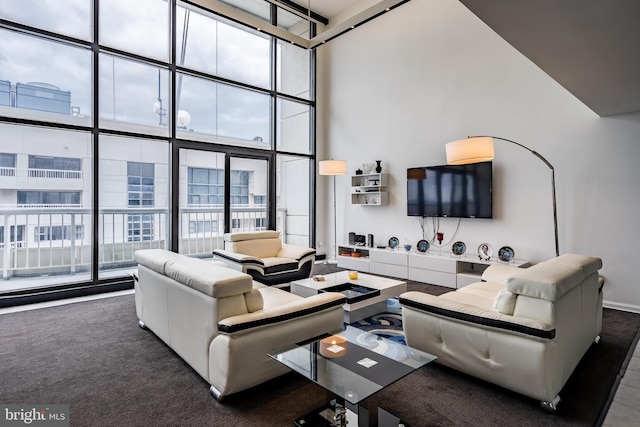 living room with dark carpet, a towering ceiling, and expansive windows