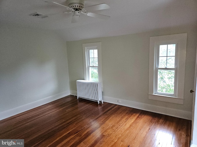 spare room with wood-type flooring, vaulted ceiling, ceiling fan, and radiator heating unit