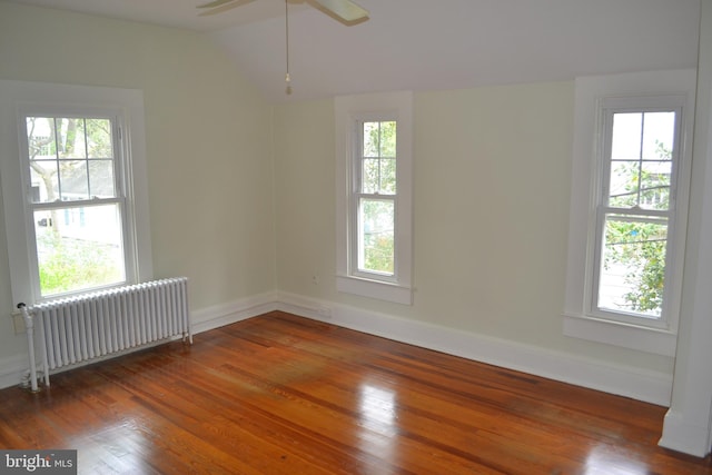 empty room featuring dark hardwood / wood-style flooring, radiator, and a wealth of natural light