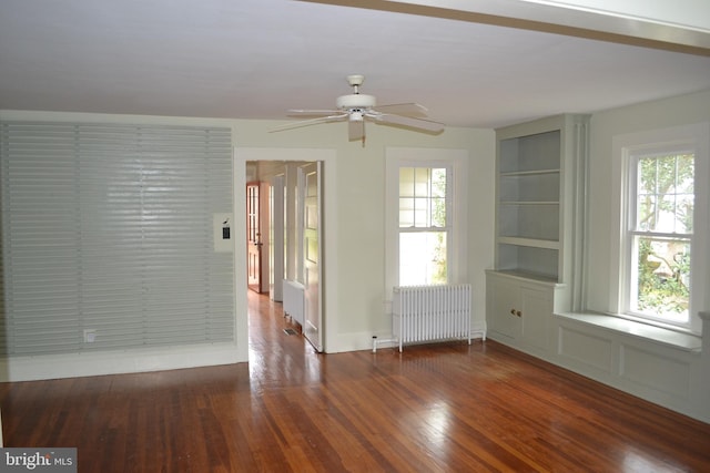 spare room with built in features, ceiling fan, hardwood / wood-style flooring, and radiator