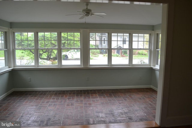 unfurnished sunroom featuring ceiling fan