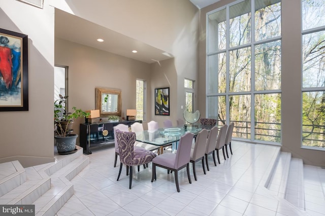 tiled dining space featuring a towering ceiling