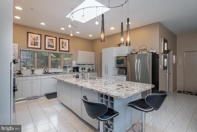 kitchen featuring appliances with stainless steel finishes, sink, white cabinets, and an island with sink