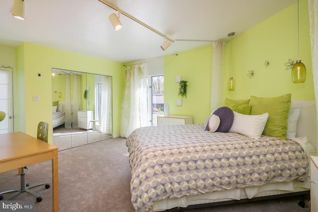 carpeted bedroom with a closet and track lighting