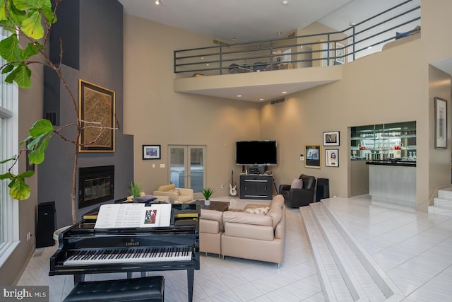 living room with a towering ceiling, a fireplace, and light tile patterned floors