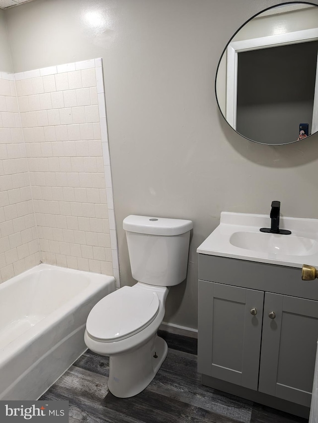 full bathroom with tiled shower / bath combo, vanity, toilet, and hardwood / wood-style flooring