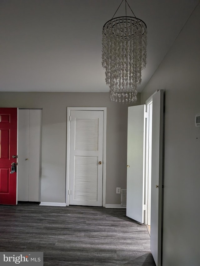 interior space with a notable chandelier and dark hardwood / wood-style flooring