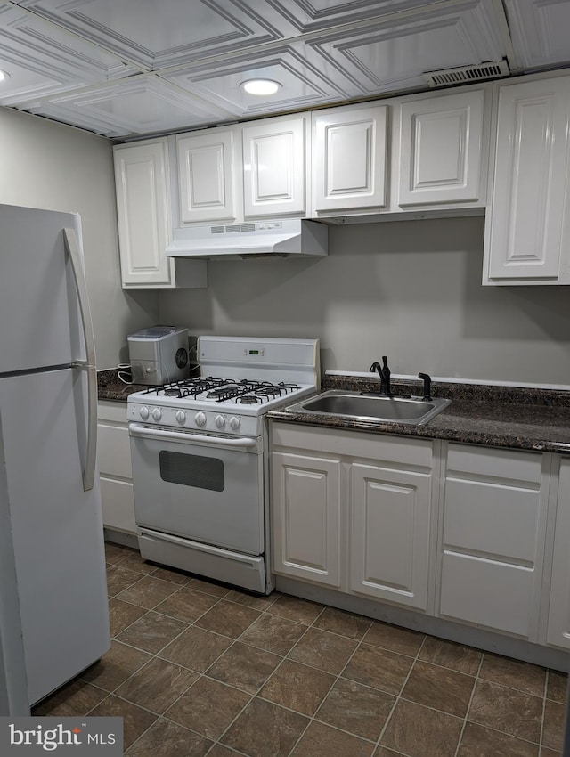 kitchen featuring white appliances, dark tile flooring, custom exhaust hood, white cabinets, and sink