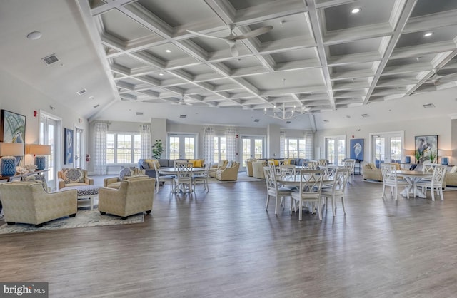 dining area featuring hardwood / wood-style flooring, a towering ceiling, and coffered ceiling