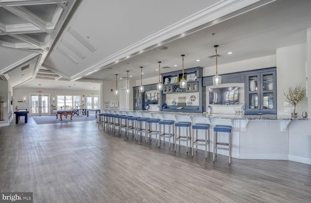 interior space with hanging light fixtures, dark hardwood / wood-style floors, light stone counters, a kitchen bar, and kitchen peninsula