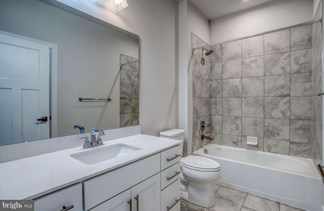 full bathroom featuring tile patterned flooring, vanity, tiled shower / bath combo, and toilet