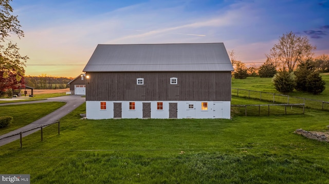 back house at dusk featuring a yard, a garage, and an outdoor structure