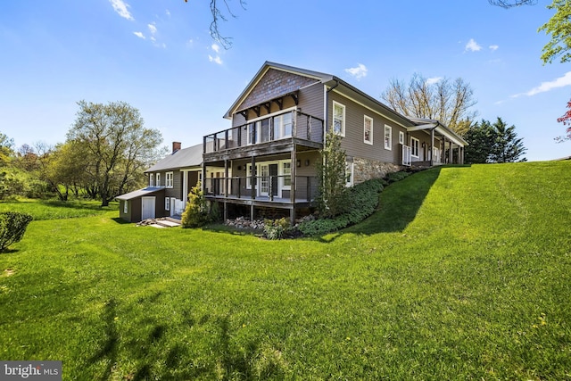 back of house featuring a wooden deck, a lawn, and an outdoor structure