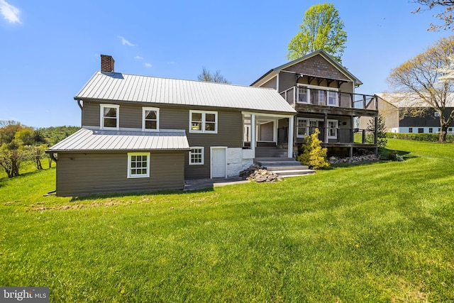 rear view of property with a balcony and a yard