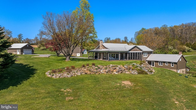 back of house featuring an outdoor structure, a garage, and a lawn