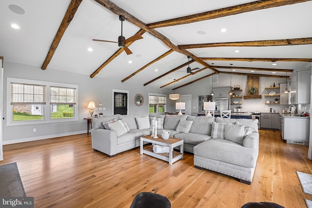 living room with sink, ceiling fan, vaulted ceiling with beams, and light wood-type flooring