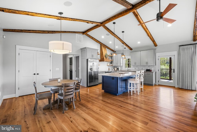 dining area with high vaulted ceiling, beamed ceiling, light hardwood / wood-style floors, and ceiling fan