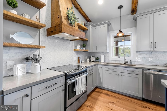 kitchen with pendant lighting, light hardwood / wood-style flooring, custom range hood, stainless steel appliances, and sink