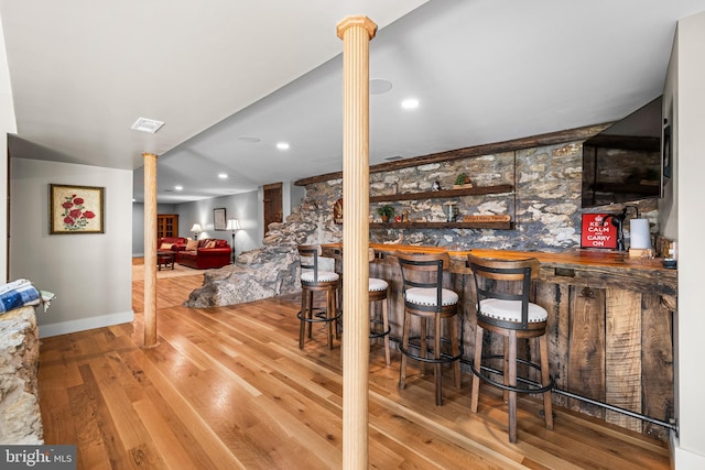 bar with ornate columns and hardwood / wood-style flooring