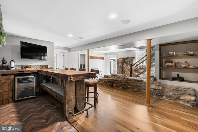 bar with butcher block countertops, wine cooler, and hardwood / wood-style flooring