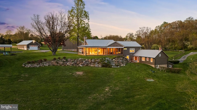 back house at dusk featuring a yard and an outdoor structure