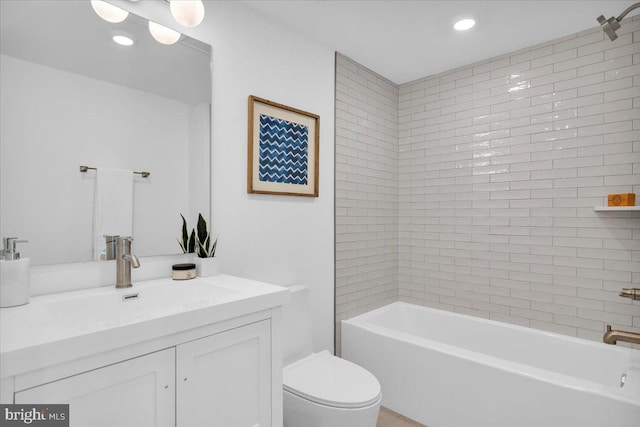 full bathroom featuring vanity, tiled shower / bath combo, and toilet