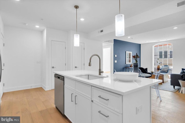 kitchen with pendant lighting, white cabinetry, sink, and an island with sink