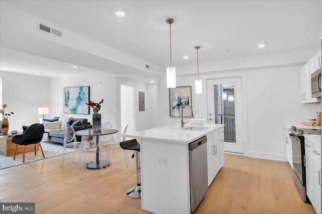 kitchen with white cabinetry, sink, appliances with stainless steel finishes, and an island with sink