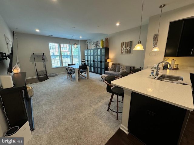 kitchen featuring carpet floors, a sink, light countertops, a kitchen bar, and open floor plan