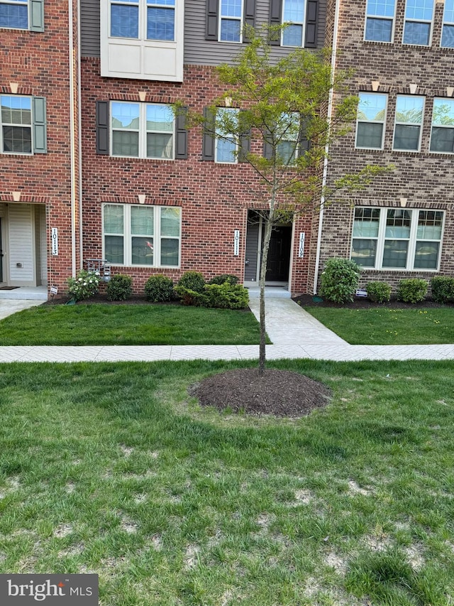 multi unit property featuring a front lawn and brick siding