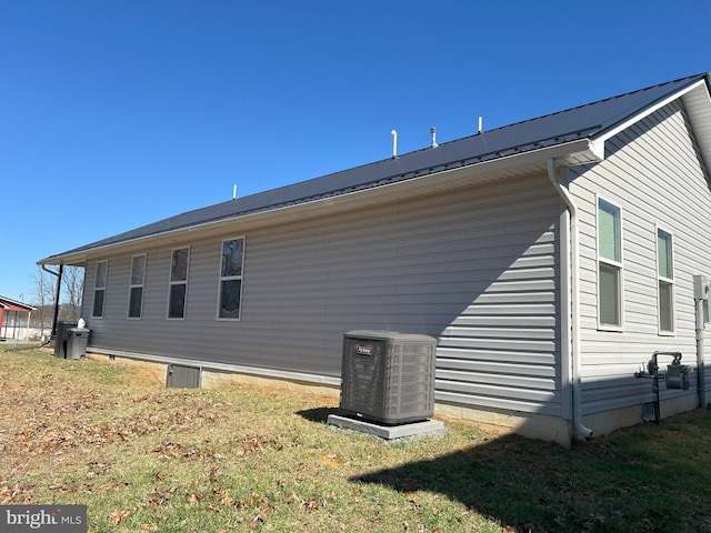 view of property exterior with central air condition unit and a lawn