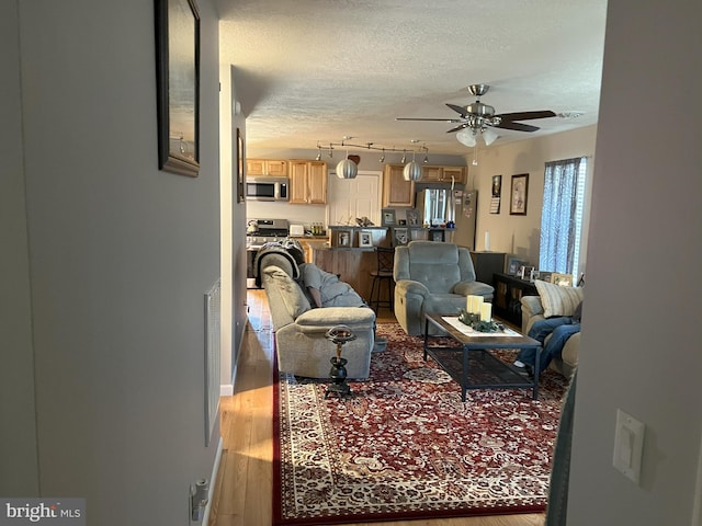 living room featuring a textured ceiling, hardwood / wood-style floors, ceiling fan, and track lighting