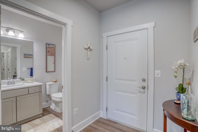 bathroom with wood-type flooring, large vanity, and toilet