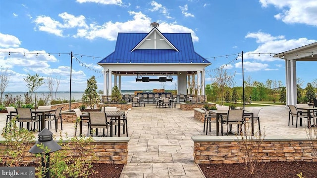 view of terrace featuring a water view, an outdoor bar, and a gazebo