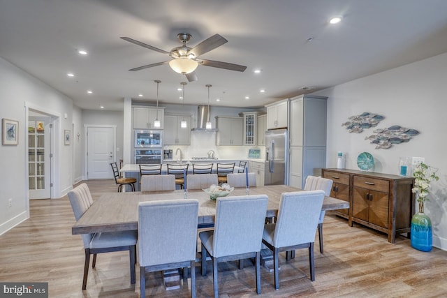 dining room with light hardwood / wood-style floors, ceiling fan, and sink