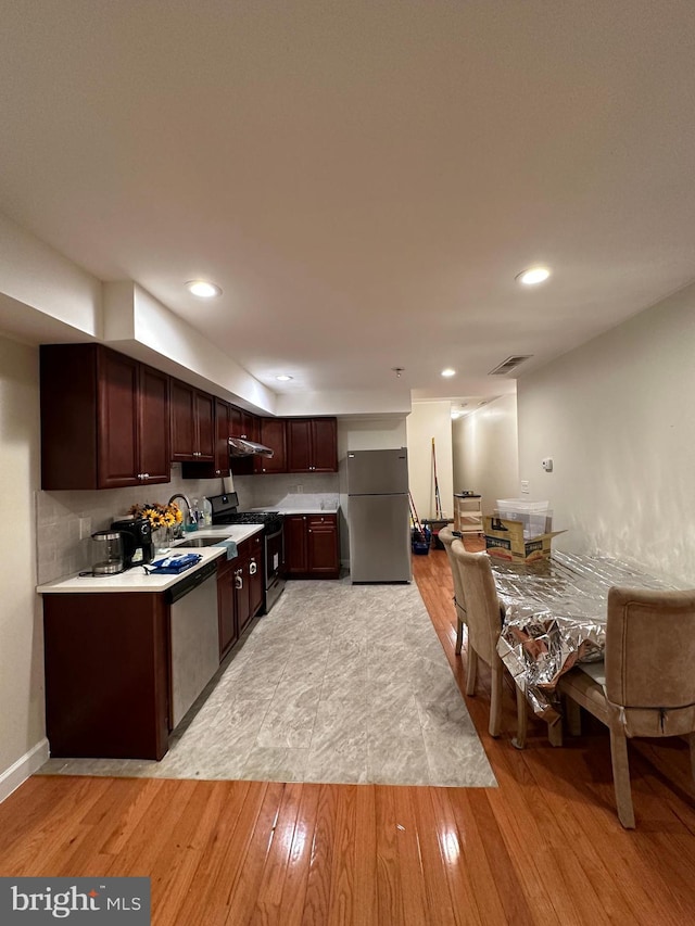 kitchen with dark brown cabinetry, sink, appliances with stainless steel finishes, and light wood-type flooring