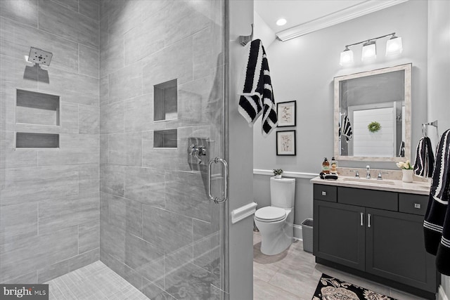 bathroom featuring oversized vanity, tile floors, a tile shower, ornamental molding, and toilet